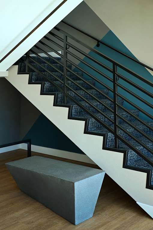 A staircase with a black metal railing and a concrete bench at the bottom.