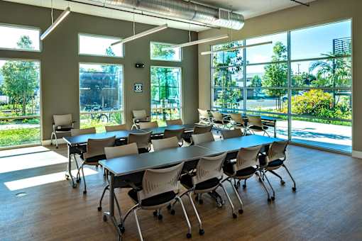 A conference room with a long table and chairs, and a view of the outside through large windows.