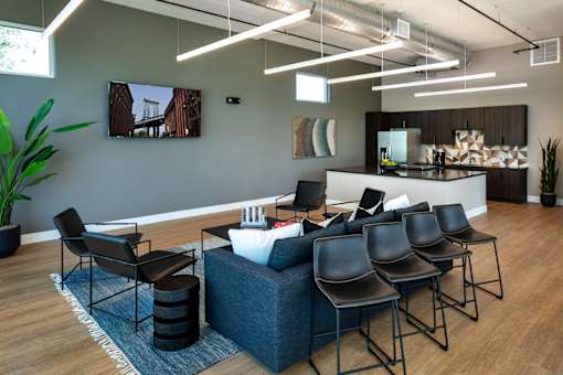 A modern waiting room with a large couch, chairs, and a flat screen TV mounted on the wall.