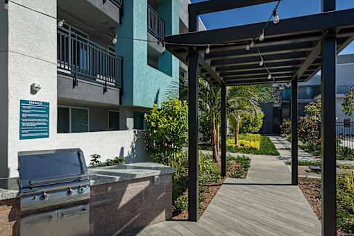 A patio with a grill and a pergola.