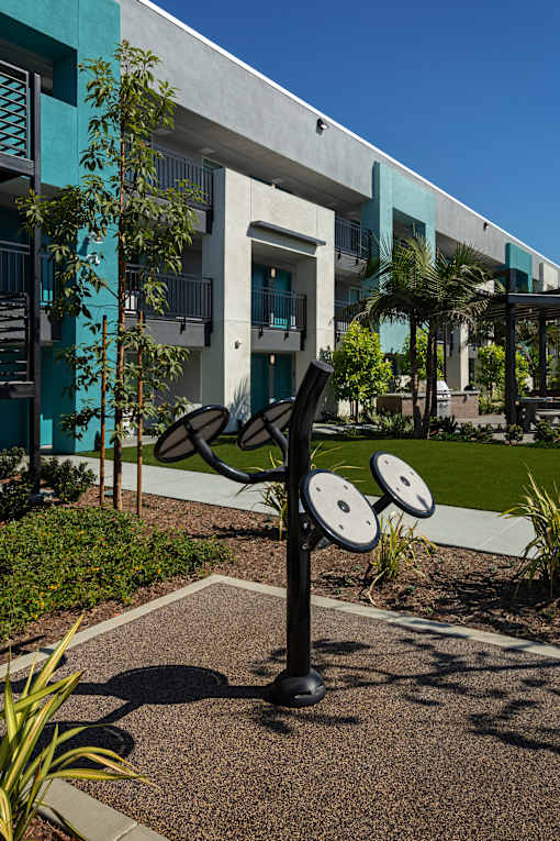 A black and white outdoor gym equipment set in front of a building.