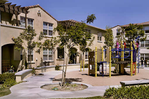 A playground with a slide and swings in front of a building.