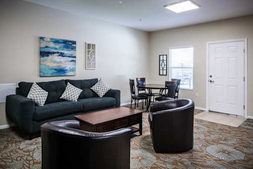 A living room with a black couch and a painting on the wall.