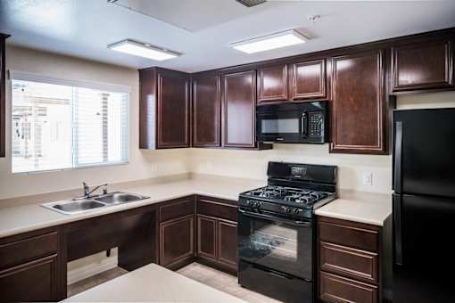 A kitchen with dark brown cabinets and black appliances.