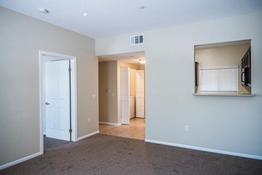 A room with a white door, a window with blinds, and a wall-mounted TV.