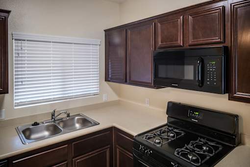 A kitchen with a black stove and a black microwave above it.
