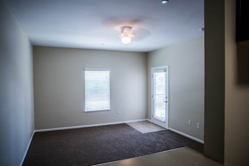 A room with a carpeted floor and a door leading to another room.