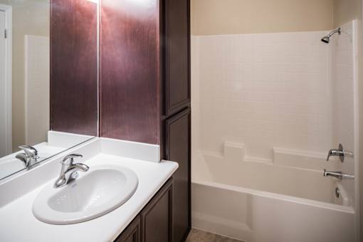 A white sink is in a bathroom with a white tub.