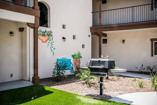 A patio with a grill and a wall mural of a blue cow.