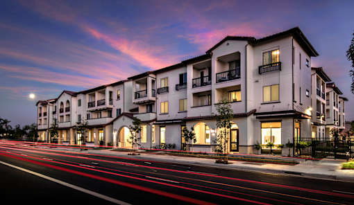 A modern apartment building with a long exposure street in front.