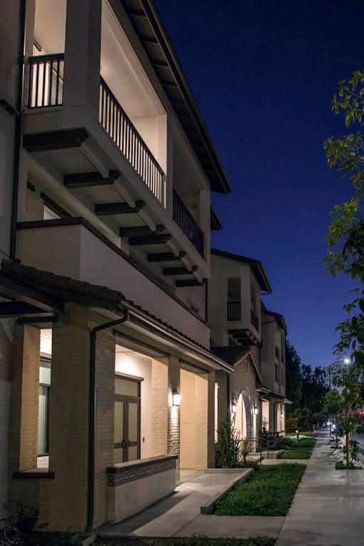 A row of houses with lit up windows and balconies.