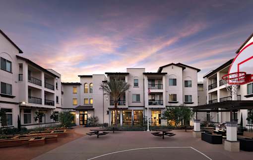A sunset view of a courtyard with a basketball hoop.
