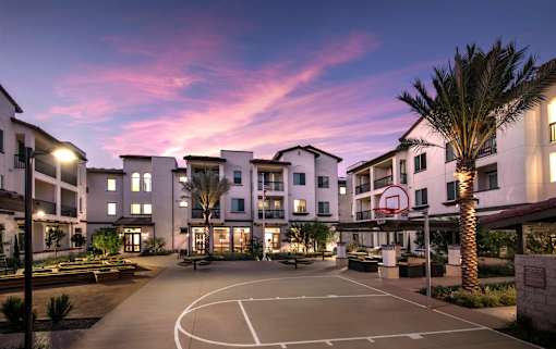 A basketball court is surrounded by apartment buildings.