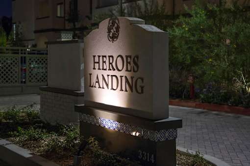A sign that says Heroes Landing stands in front of a building.