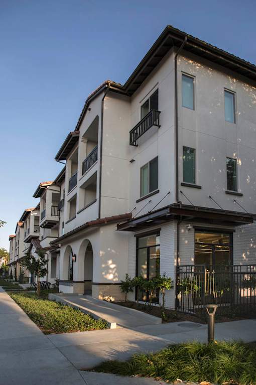 A row of modern townhouses with balconies and black railings.