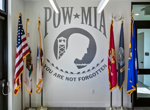 A wall with a sign that says "POW-MIA" and flags on either side.