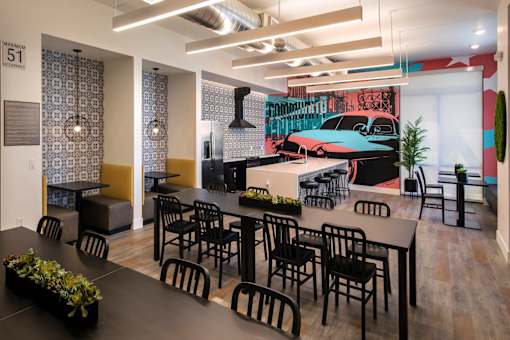 A room with a long table and chairs in front of a wall with a vintage car poster.