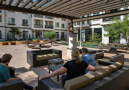 People are sitting on the benches under the wooden roof.
