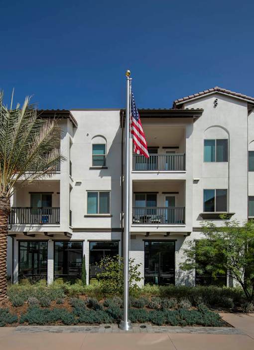 A white building with a balcony and a flag on a pole.