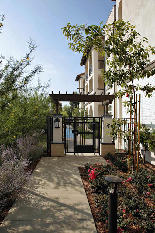 A gate with a black metal railing and a wooden pergola above it.