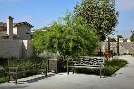 A bench in a garden with a house in the background.