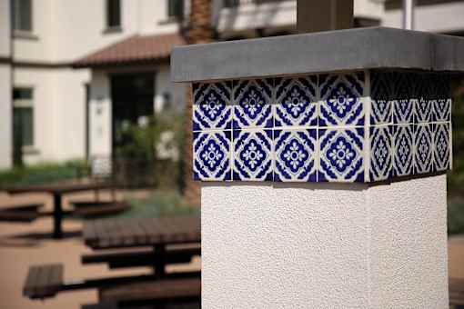 A blue and white tile is attached to a white wall.