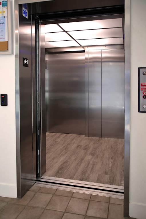 A stainless steel elevator with a black control panel and a star symbol on the wall.