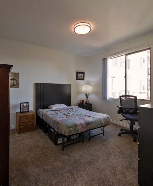 A bedroom with a bed, chair, and nightstand.