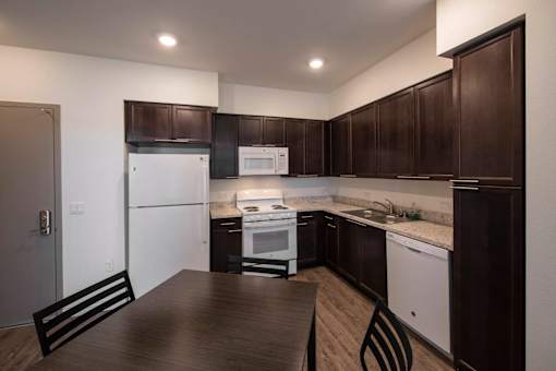 A kitchen with dark brown cabinets and white appliances.