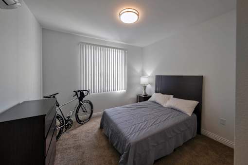 A bedroom with a bed, nightstand, and a bicycle.