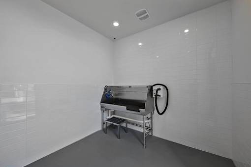 A white tiled room with a table and a hose.