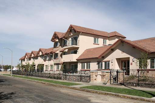 A row of houses with brown roofs and black fences.