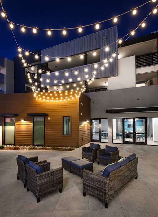 A patio with wicker furniture and string lights.