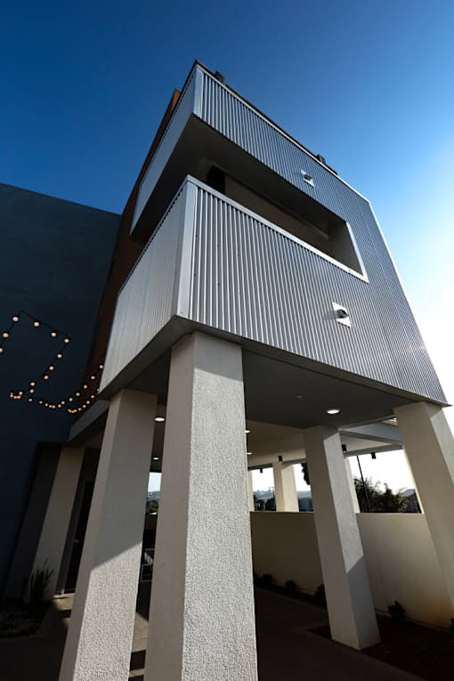 A modern building with a unique design featuring a series of white columns and a dark facade.