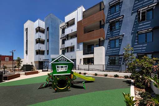 A playground with a green slide and a white building in the background.