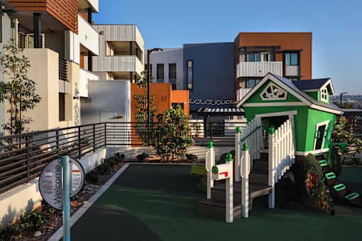 A playground with a green slide and a white fence.