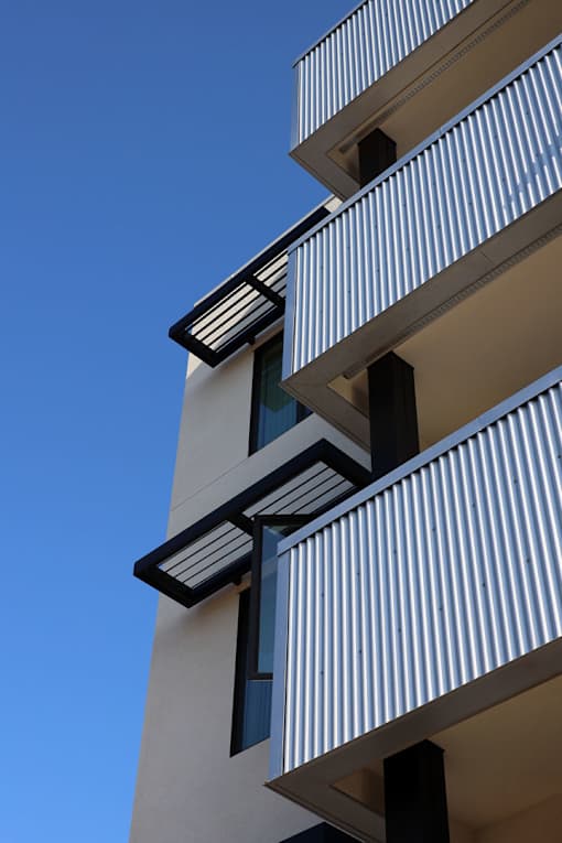 A tall building with balconies and a blue sky in the background.
