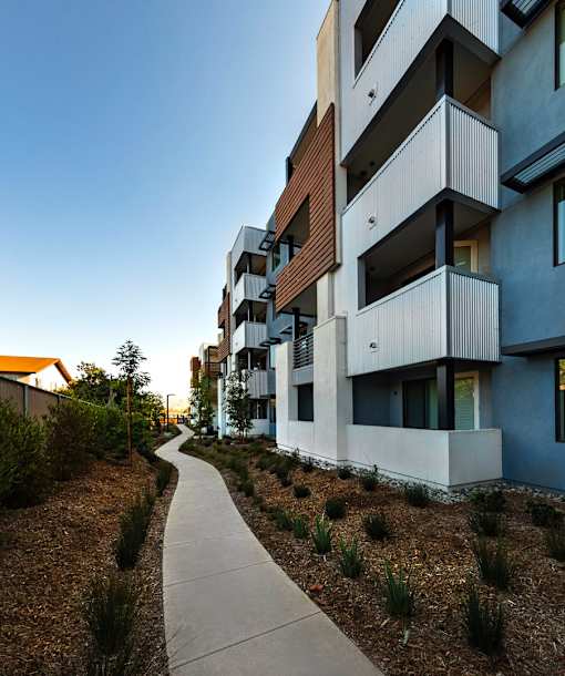 A modern apartment building with a walkway in front.