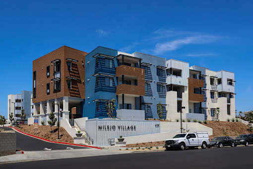A modern building complex named Milejo Village under a clear blue sky.