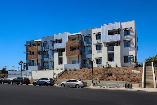 A modern multi-story building with a parking lot in front.