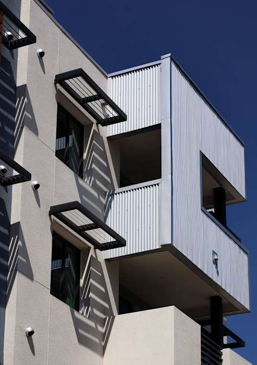 A white building with black balconies and windows.
