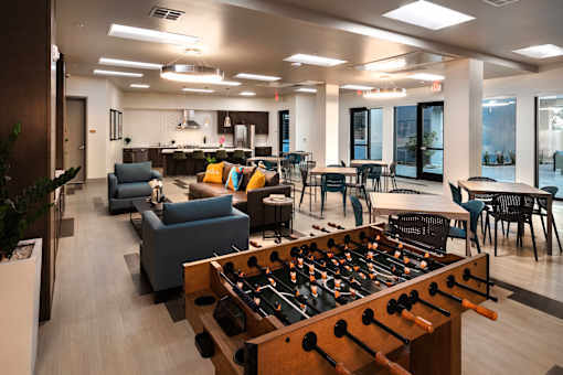 A foosball table is in the middle of a room with couches and chairs.