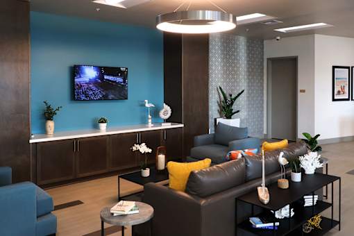 A modern living room with a grey sofa, a coffee table, and a TV mounted on the wall.
