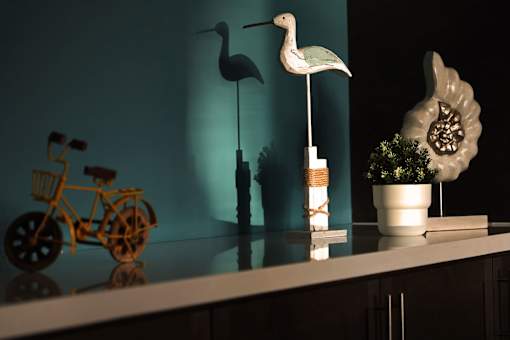 A white bird statue stands on a shelf next to a yellow bicycle.