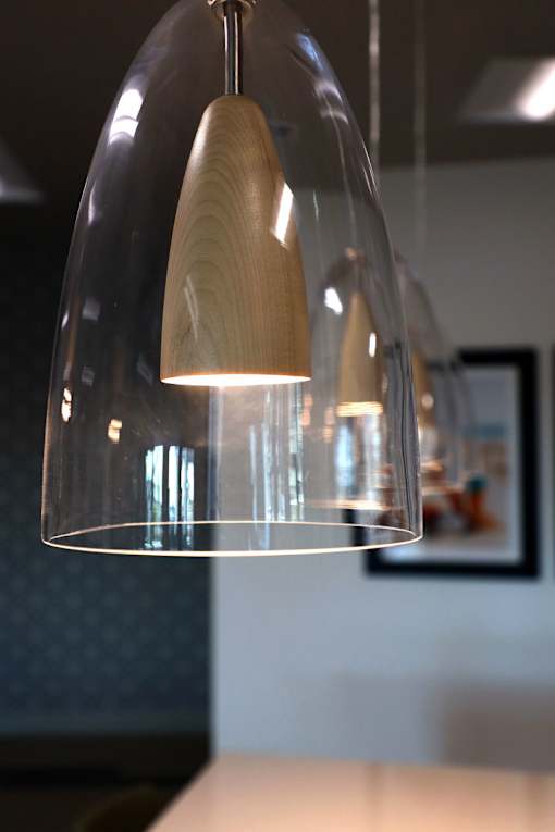 A modern hanging lamp with a wooden shade is suspended from the ceiling.