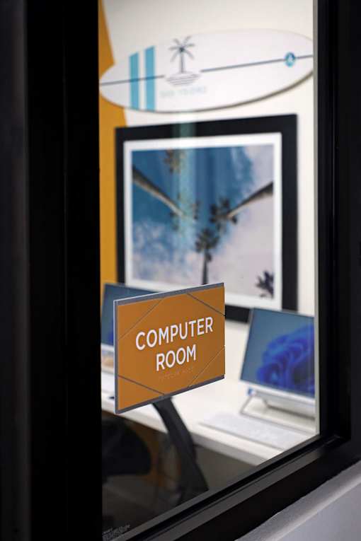 A sign that says Computer Room is on a stand in front of a computer.
