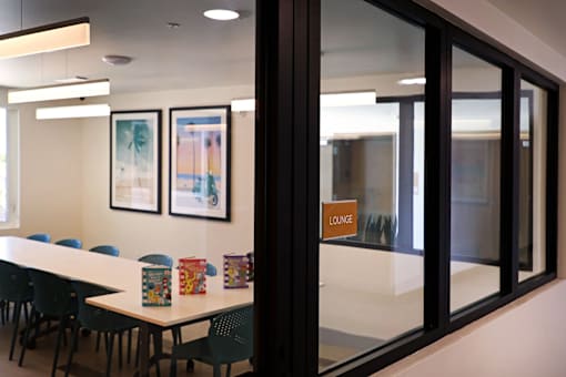 A conference room with a long table and chairs, a framed picture on the wall, and a sign that says "LOUNGE".