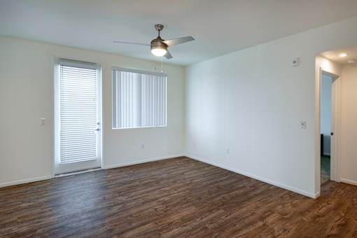 A room with a ceiling fan and wooden flooring.