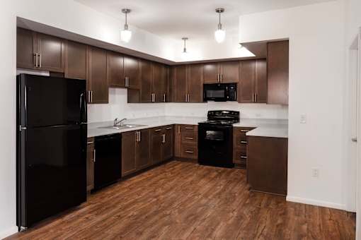 A kitchen with wooden floors and dark brown cabinets.