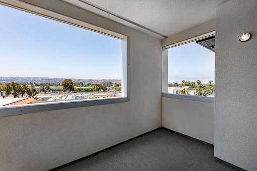 A room with two windows overlooking a parking lot.
